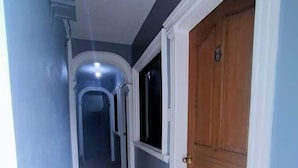 A hallway with a wooden door, a window, and a ceiling light fixture. - Maritonies Place (Coron)