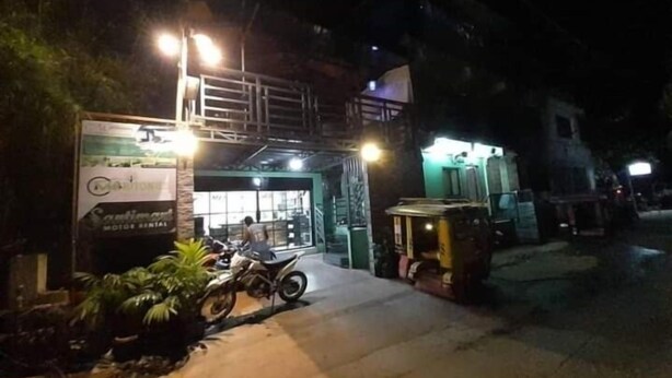A building with a sign for a motor rental service, a motorcycle parked in front, and a tuk-tuk nearby. - Maritonies Place (Coron)