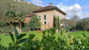 Ein zweistöckiges Haus mit gepflegtem Rasen und einer Steinmauer.