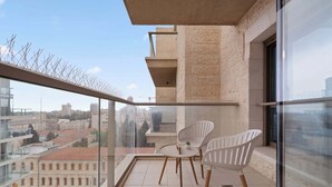 A balcony with two white chairs, a small table, and a potted plant. - Luxurious 1BDR Terrace Parking in City Central (Jerusalem)