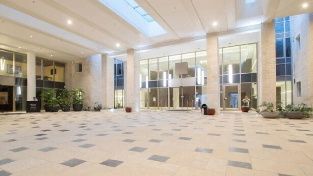 A spacious lobby with a high ceiling, large windows, and a tiled floor. - Luxurious 1BDR Terrace Parking in City Central (Jerusalem)