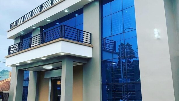 En moderne bygning med en toetagers struktur, store glasvinduer og en balkon med metalgelændere.