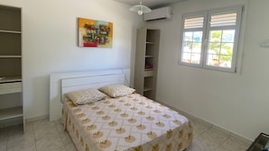 Un dormitorio con cama, ventana con persianas, ventilador de techo y aire acondicionado de pared.