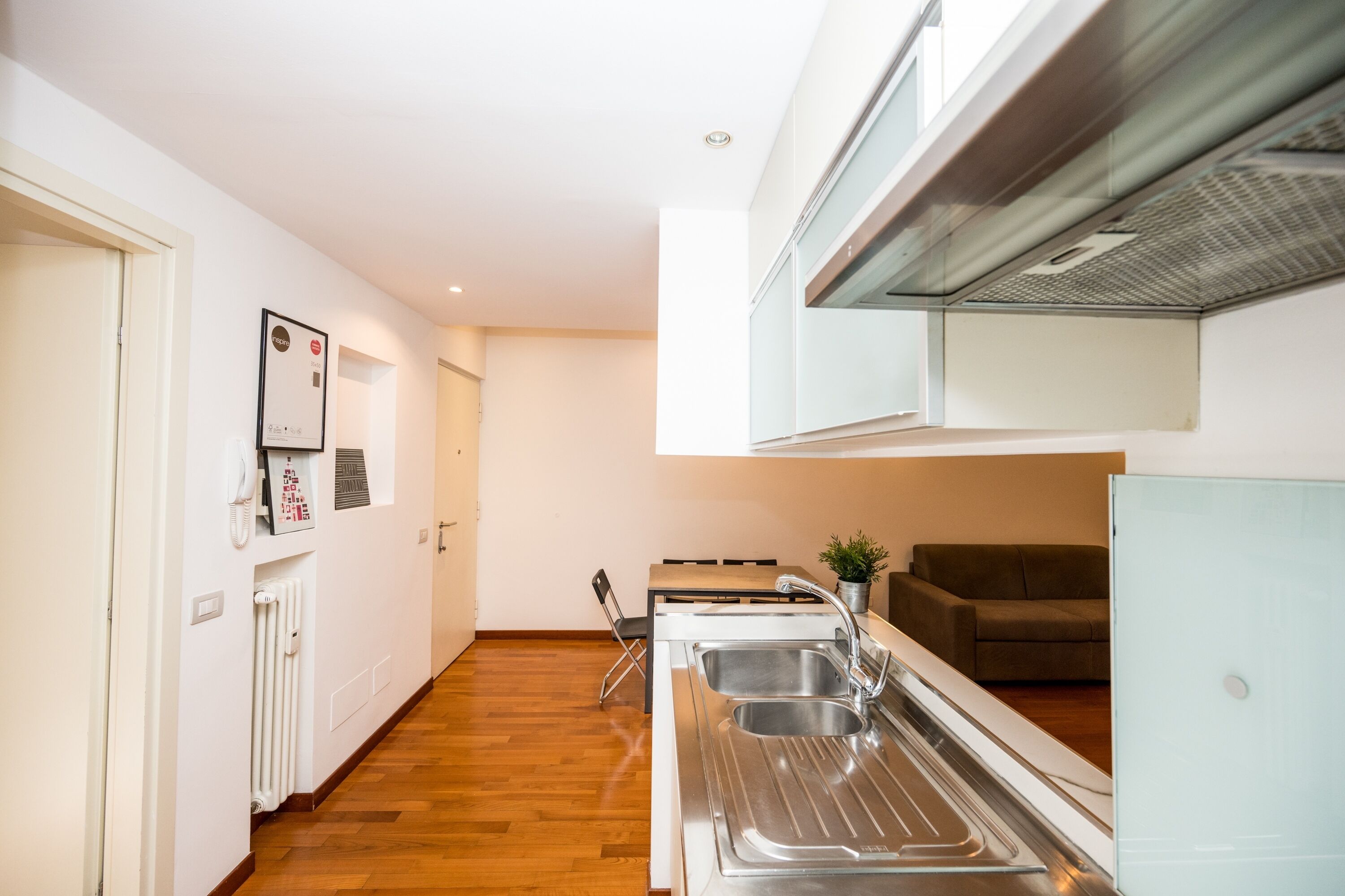 Una cocina moderna con un lavamanos integrado, una zona de comedor con mesa y sillas, y un sofá al fondo.