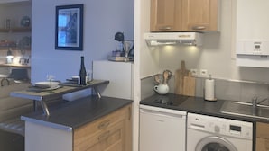Cocina compacta con muebles de madera, lavavajillas, estufa y fregadero.