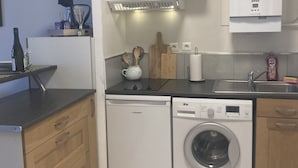 Una cocina compacta equipada con lavavajillas, lavadora y horno empotrado.