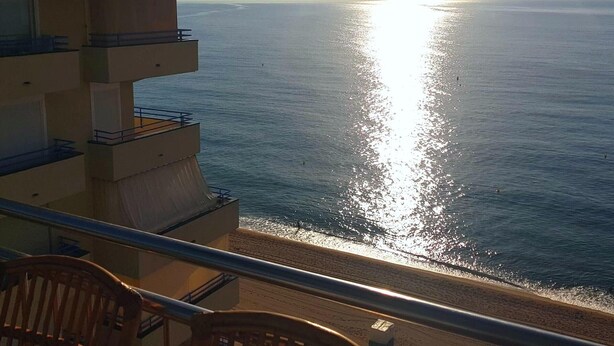 Ein Balkon mit Blick auf das Meer und die Sonne, die sich im Wasser spiegelt.