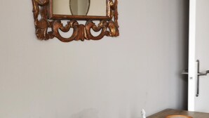 Ein Badezimmer mit einem Holzkonsolenunterschrank, einem Spiegel mit aufwendiger Rahmung und einer Tür.