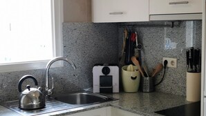 Eine Küche mit einem Edelstahlkocher, einem Spülbecken und einer Arbeitsfläche mit Entsafter und Geschirr.