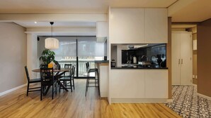 Una cucina moderna con mobili bianchi, un piano di lavoro nero e un'area pranzo con tavolo e sedie in legno.
