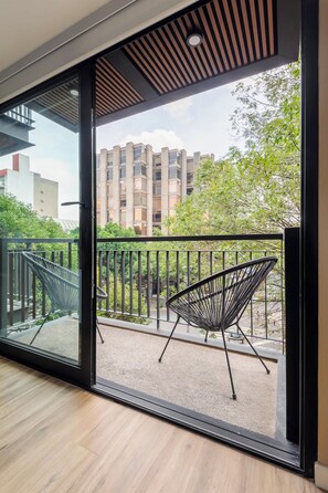 A balcony with a modern chair and a view of a building with multiple windows.