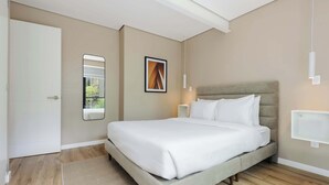 Ein modernes Schlafzimmer mit einem großen Bett, einem Nachttisch, einem Spiegel und einer Wandleuchte.