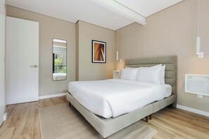 Un dormitorio moderno con una cama grande, una mesita de noche, un espejo y una lámpara de pared.