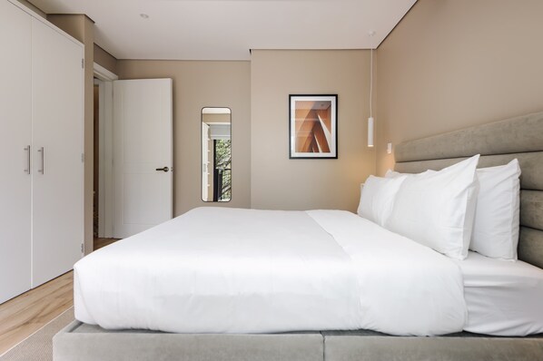 A modern bedroom with a large bed, a wardrobe, and a framed picture on the wall.