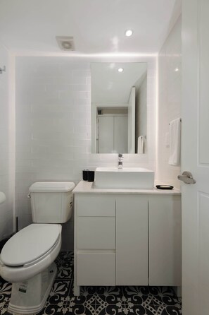 Une salle de bain moderne avec des toilettes, un lavabo et un miroir.