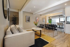 A modern living room with a sofa, a coffee table, and a dining area with a table and chairs. - w* | Vibrant 2BR with Balcony in Condesa (Ciudad de México)
