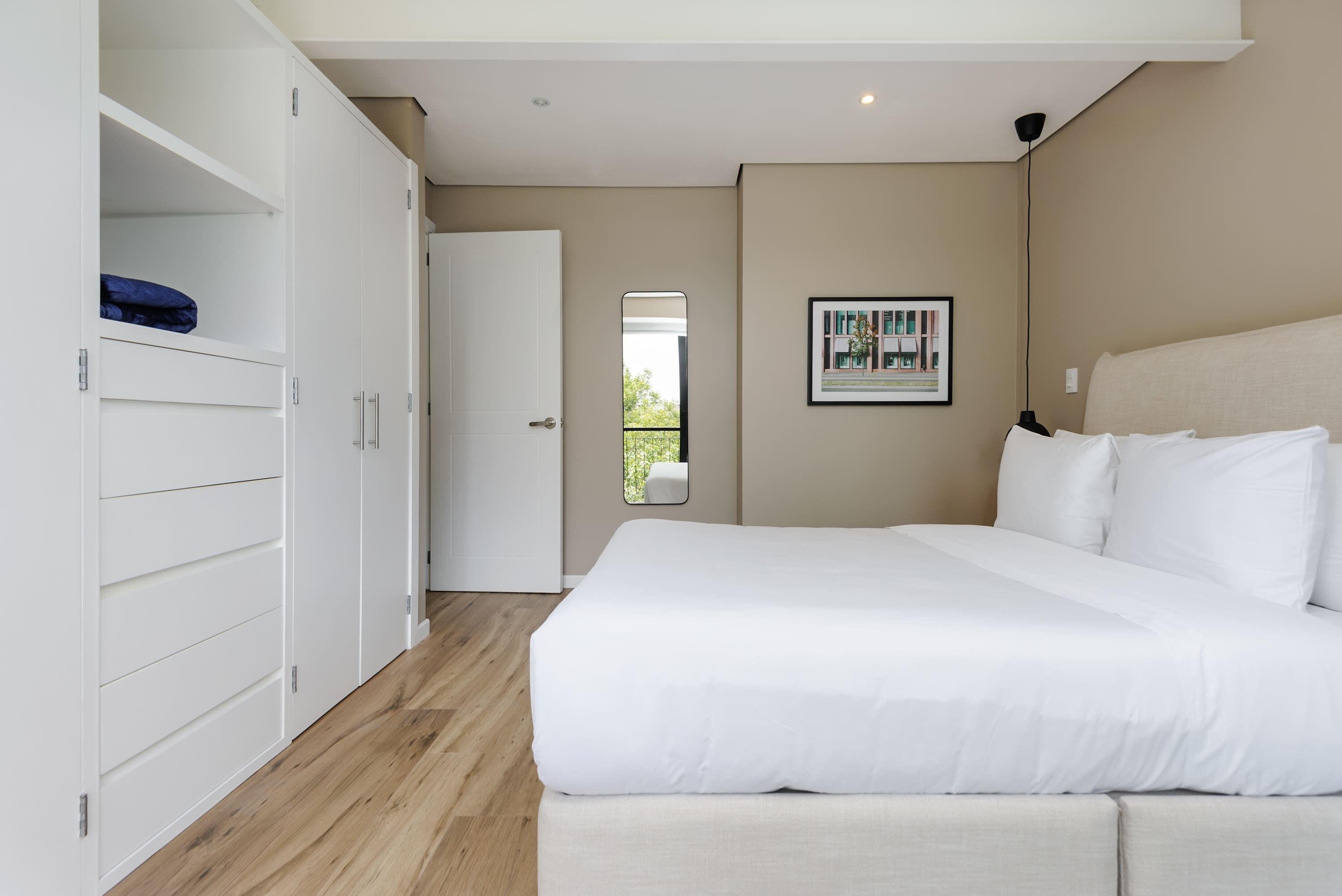 Un dormitorio con una cama grande, un armario y un cuadro en la pared.