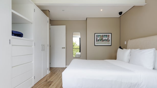 Ein Schlafzimmer mit einem großen Bett, einem Kleiderschrank und einem gerahmten Bild an der Wand.