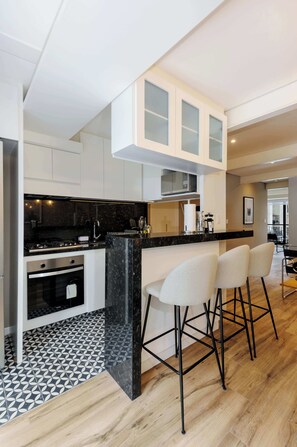 A modern kitchen with a central island, bar stools, and a patterned floor.