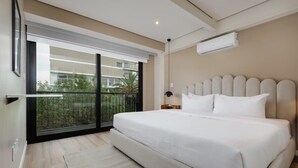 A modern hotel room with a large bed, a balcony with a view of buildings and greenery, and an air conditioning unit on the wall. - w* | Vibrant 2BR with Balcony in Condesa (Ciudad de México)