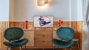 Ein Zimmer mit zwei türkisfarbenen Stühlen, einem Holzkabinett und einem gerahmten Bild an der Wand.