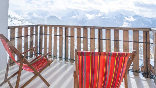 Ein Balkon mit Holzwerteln und zwei gestreiften Hängematten.