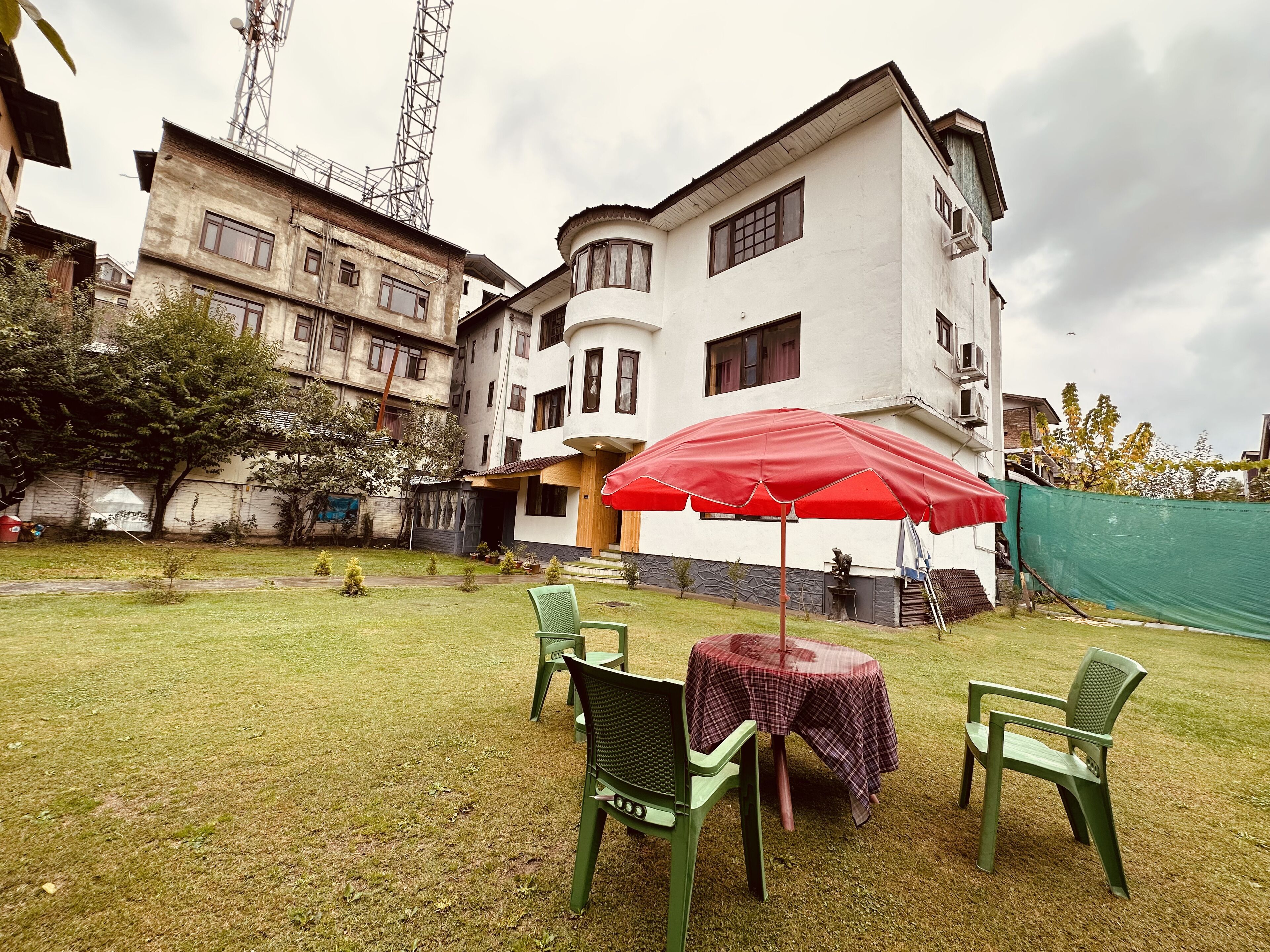 Un patio con una mesa y sillas bajo un paraguas rojo, rodeado de edificios.
