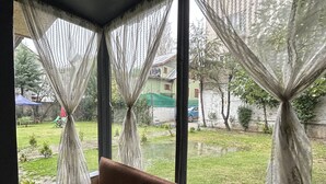 A room with a window view of a green lawn and a building in the distance. - The Iceland Hotel Srinagar (Srinagar)