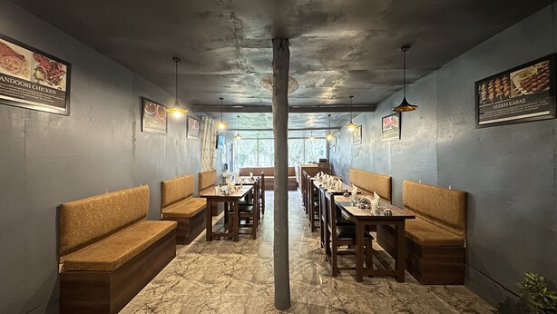 A restaurant with booths and tables, marble flooring, and pendant lighting. - The Iceland Hotel Srinagar (Srinagar)