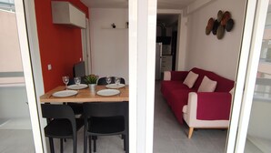 Comedor con mesa de madera para cuatro personas, sillas negras y pared roja.