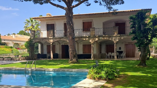 Um edifício de dois andares com piscina, área de estar ao ar livre e gramado bem cuidado.