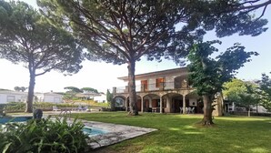 Uma villa com piscina, área de estar externa e gramado bem cuidado.