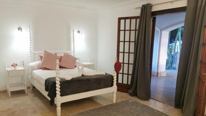 Quarto com cama, mesas de cabeceira, tapete e vista para o exterior.