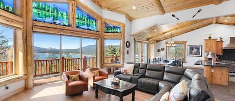 A spacious living room with a large window overlooking a scenic view, a fireplace, and a kitchen area.