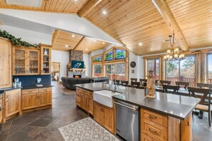 A spacious kitchen with wooden cabinets, a large island, and a stone fireplace.