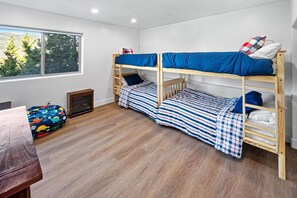 A bunk bed room with a window, a small table, and a bean bag chair. - Grand Summit: LUXURY 5000+Sq Ft Log Style Estate! Lake & Sunset Views! HOT TUB! PET FRIENDLY 🐾! Home Theater! Game Room! Central AC! (Big Bear Lake)