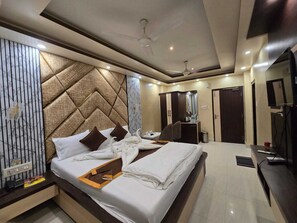 A hotel room with a large bed, a desk, a wardrobe, and a ceiling fan. - HOTEL BINAPANI DELUXE 1 (Rampurhat)