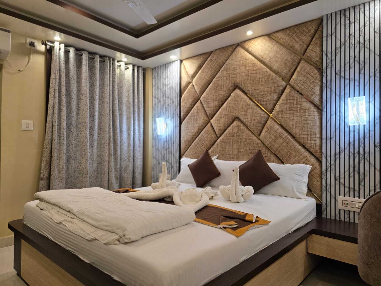 A modern hotel room with a large bed, a bedside table, and a headboard with a geometric pattern.
