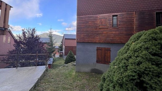 Edifício residencial com fachada de madeira e uma pequena janela.