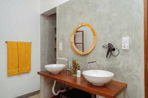 A bathroom with two sinks, a wooden vanity, a mirror, and a yellow towel. - Babu Villas (Jambiani)