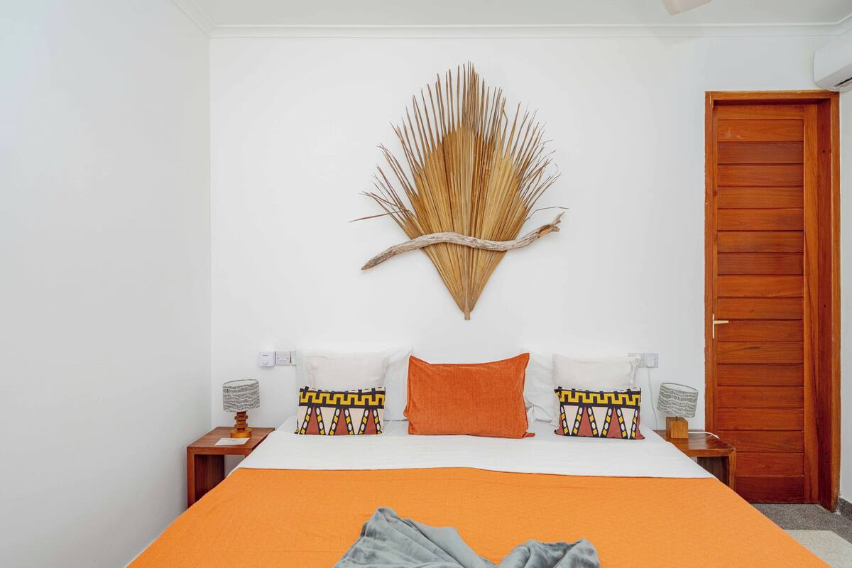 Un dormitorio con una cama, un adorno en la pared y una puerta de madera.