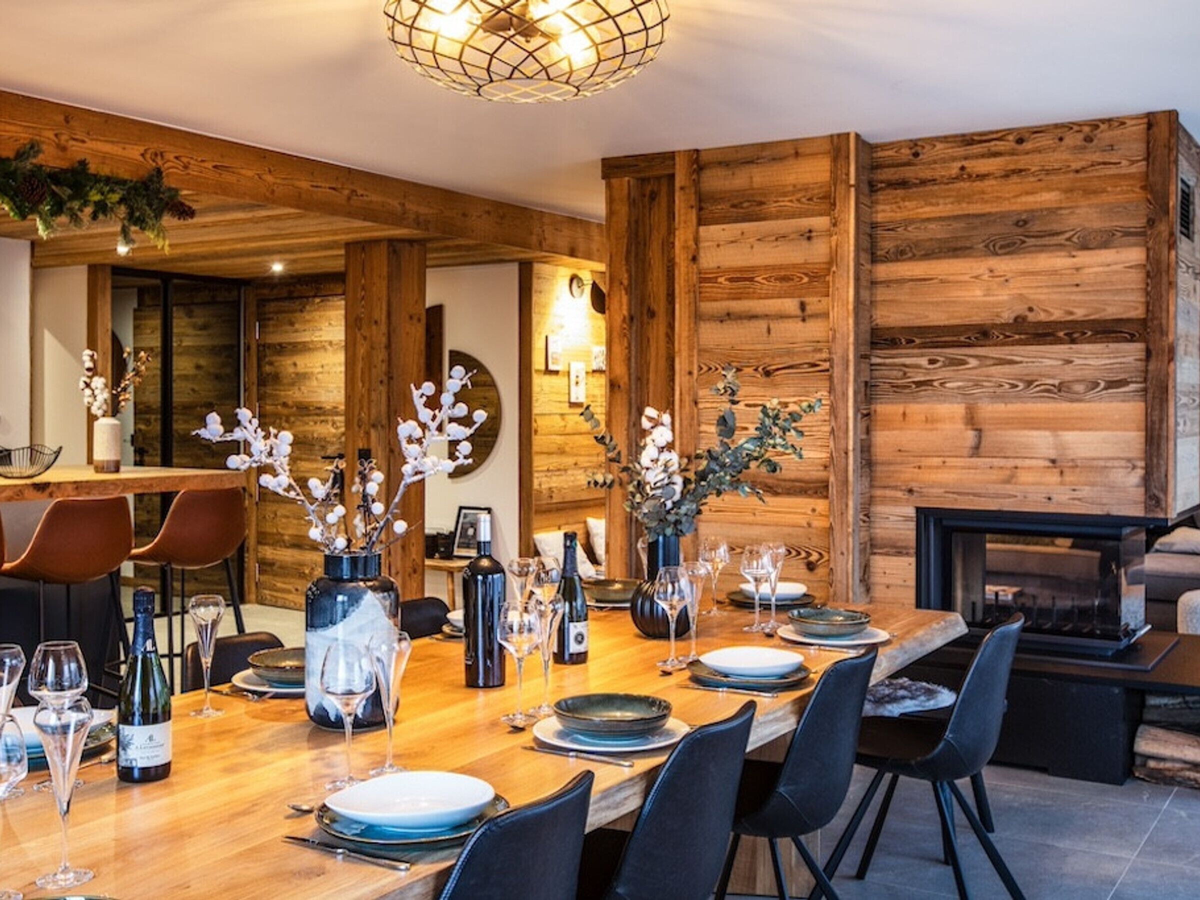 A dining area with a wooden table set for four, surrounded by chairs.