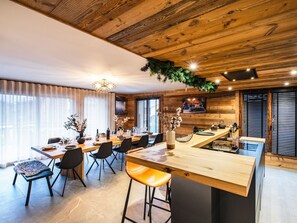 Een moderne keuken met houten details, een eetgedeelte met stoelen en een bar met krukken.