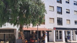 Un patio con un árbol, asientos al aire libre y un edificio con un letrero para lavandería autoservicio.