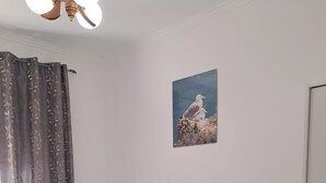 Un dormitorio con cama, almohadas, mesita de noche, espejo y un cuadro en la pared.