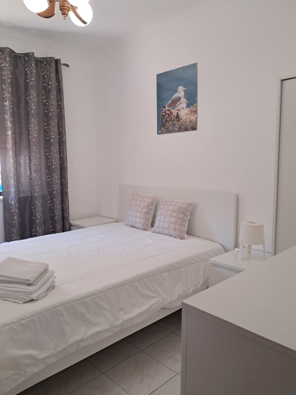 Une chambre à coucher avec un lit, des oreillers, une table de chevet, un miroir et un tableau accroché au mur.