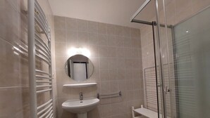 A bathroom with a pedestal sink, a mirror, a glass shower enclosure, and a towel rack. - Studio at the foot of the slopes with balcony and pets allowed (Les Deux Alpes)