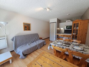 Un espacio habitable compacto con sofá, mesa de comedor y kitchenette.