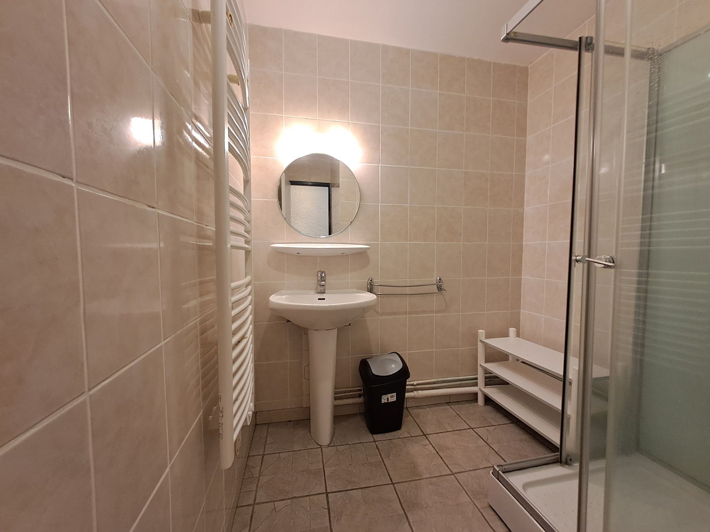 A bathroom with a sink, mirror, and shower.