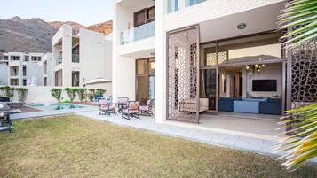 Enjoy a relaxing stay in a spacious room with an outdoor seating area overlooking a well-maintained lawn and pool.